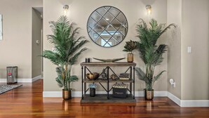 A wooden console table with decorative items and plants, a round mirror, and wall sconces. - Welcome To Your New Favorite Spot! Tree Top Views & Lots Of Room! (Salem)