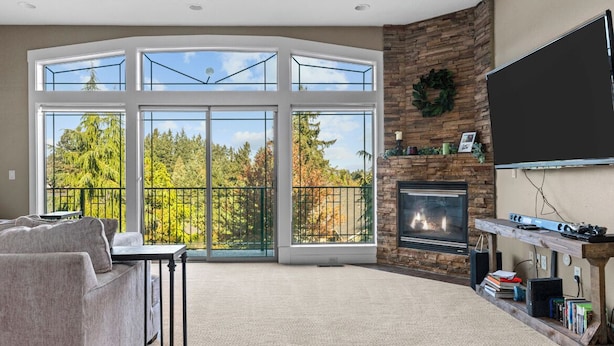 A spacious living room with a large sliding glass door leading to a balcony, a fireplace, and a mounted flat-screen TV. - Welcome To Your New Favorite Spot! Tree Top Views & Lots Of Room! (Salem)