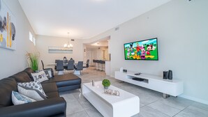 A modern living room with a sofa, coffee table, TV, and a white entertainment unit.