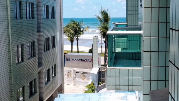 Blick auf einen Strand von einem Hochhaus aus, mit einem Schild für 'RIE RODONAVES'.