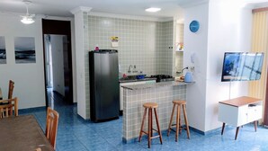 Eine kleine Küche mit Kühlschrank, Spüle und Barhocker.