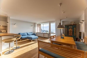 En moderne stue med et træspisebord, en blå sofa og en træbænk.
