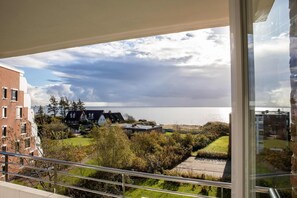 Vista da un balcone su un corpo d'acqua, con edifici e vegetazione sullo sfondo.
