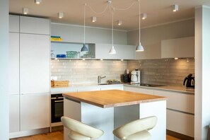 Una cucina moderna con mobili bianchi, un'isola in legno e luci a sospensione.
