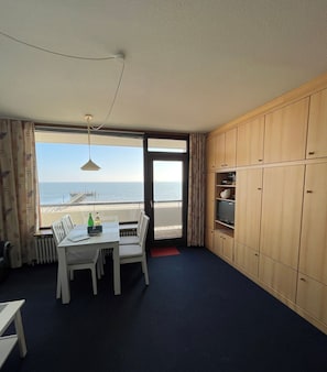 Una habitación con vista al mar, una mesa de comedor con sillas, una lámpara de techo y armarios de madera.