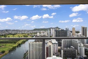 A high-rise building with multiple floors, large windows, and a view of a river and cityscape.