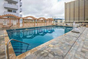 A swimming pool with a stone deck, a lifeguard stand, and a warning sign.
