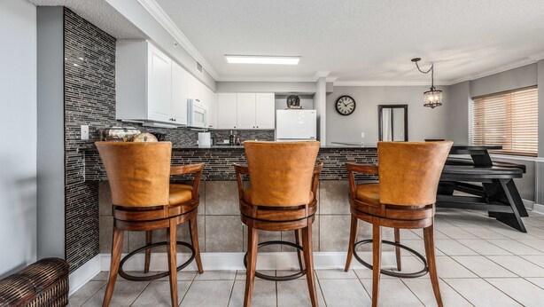 A modern kitchen with a central island, bar stools, and a dining table. - Dune Pointe 102 * Fall Rates Reduced * Salt Water Vacations (Fort Walton Beach)