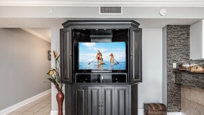 A modern living room with a large flat-screen TV mounted on a dark wooden cabinet. - Dune Pointe 102 * Fall Rates Reduced * Salt Water Vacations (Fort Walton Beach)