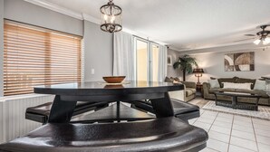 A modern living room with a dining area, featuring a dark wooden table, leather chairs, and a ceiling fan. - Dune Pointe 102 * Fall Rates Reduced * Salt Water Vacations (Fort Walton Beach)