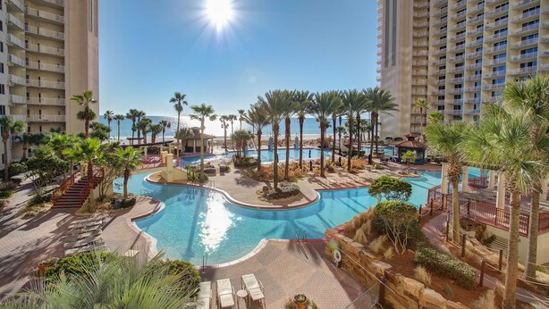 A resort pool area with palm trees, a circular pool, and a view of the ocean. - 2 Bedroom in Shores of Panama - Same floor reserved parking and stunning views! (Panama City)