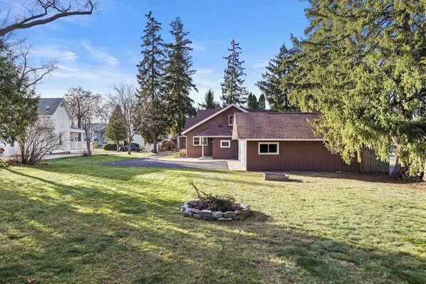 A residential house with a front yard, driveway, and a small garden area.