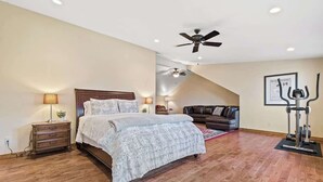 Ein Schlafzimmer mit einem Bett, einem Nachttisch, einer Lampe, einem Deckenventilator, einem Laufband und einem gerahmten Bild an der Wand.