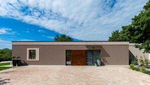 Un bâtiment moderne doté d’un toit plat, d’une grande porte d’entrée et d’une petite fenêtre sur le côté gauche.
