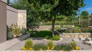 Un jardin aménagé avec un mur en pierre, un arbre et diverses plantes.