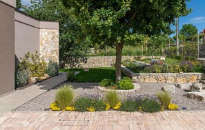 A landscaped garden with a stone wall, a tree, and various plants.