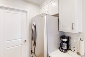 Compact kitchen with a stainless steel refrigerator, ice maker, and a coffee maker.