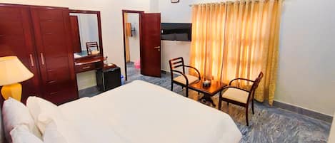 Una habitación de hotel con cama, escritorio, silla, espejo y televisor.