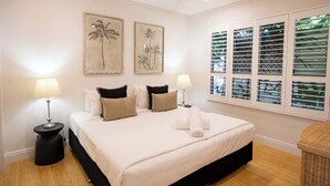 A bedroom with a bed, two wall-mounted lamps, a ceiling fan, and a window with blinds. - Sea La Vie - Port Douglas Villa (Port Douglas)