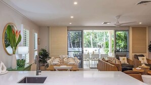 A modern kitchen with a dining area, large windows, and a view of the outdoors. - Sea La Vie - Port Douglas Villa (Port Douglas)