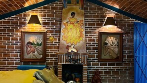 A cozy room with a brick wall, a fireplace, a bed with pillows, and a ceiling fan. - Casita. W PRIVATE POOL (Ajijic)