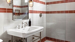 A bathroom with a white sink, mirror, and shower.