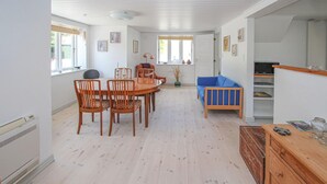 Um quarto espaçoso com uma mesa de jantar e cadeiras, um sofá azul e um armário de madeira.
