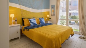 A bedroom with a bed, nightstands, a window, and a view of the outside. - Apartment Emma by Interhome (Badesi)