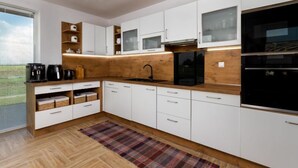 Une cuisine moderne avec des meubles blancs, un plan de travail en bois, un réfrigérateur noir et un four à micro-ondes encastré.