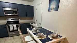 A compact kitchen with a dining table set for four, equipped with a microwave, stove, and oven. - Zen space @ Harker Heights (Harker heigths)
