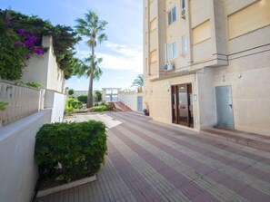 A corridor with a tiled floor, a palm tree, and a building with a door and windows. - Casita Blanca by Interhome (Calpe/Calp)