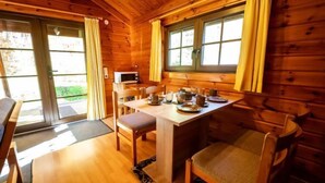 Una cabaña de madera con una mesa de comedor para dos, un microondas y vistas al exterior.