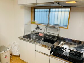 A compact kitchen with a sink, stove, and a window above the sink.