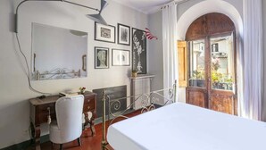 Un dormitorio con cama, escritorio, silla, un espejo grande y una ventana con cortinas.