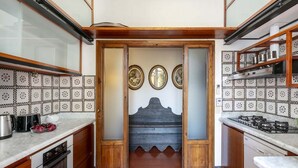 Una cocina con salpicadero de azulejos, armarios de madera, una estufa y un banco decorativo con obras de arte en la pared.
