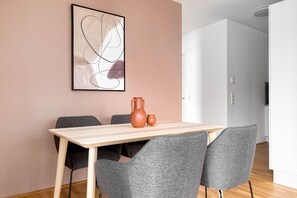 Un comedor con una mesa de madera, sillas grises y un florero sobre la mesa.