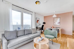 Una sala de estar moderna con un sofá gris, una mesa de centro redonda y un comedor con una mesa y sillas.