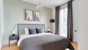 Ein modernes Schlafzimmer mit einem Bett, Nachttischen, einer Lampe und Kunstwerken an der Wand.