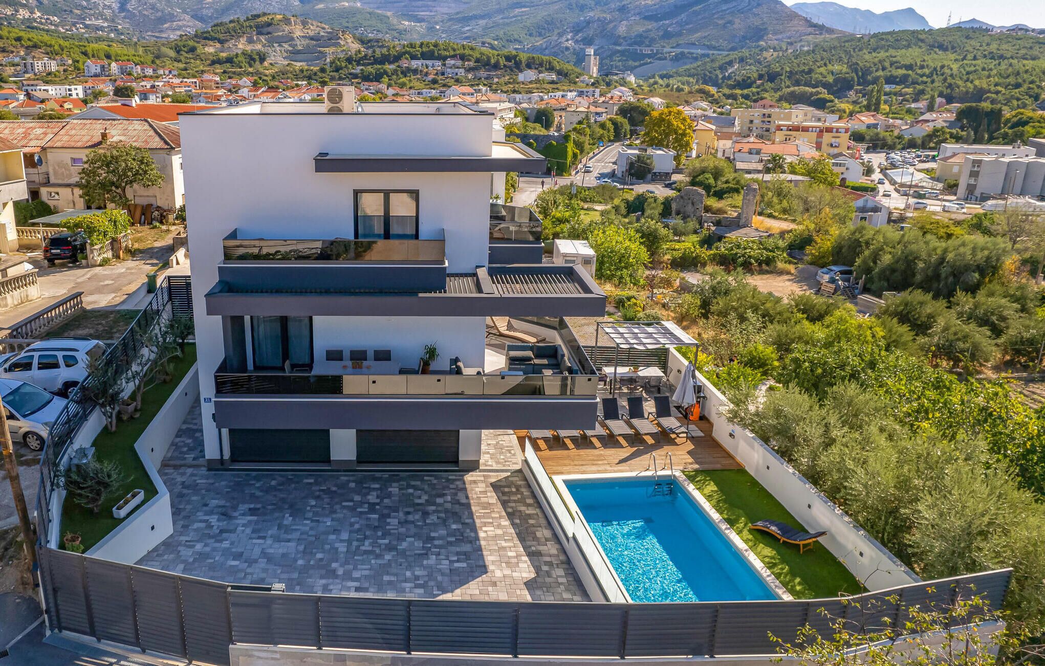 A modern multi-story house with a rooftop pool and a view of the surrounding area.