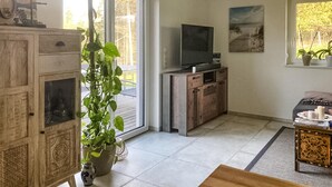 Ein Wohnzimmer mit Fernseher, Holzschränken, einer Topfpflanze und einem Bild an der Wand.
