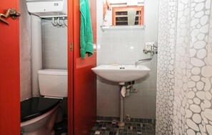Een kleine badkamer met toilet, wastafel en een handdoek aan de deur.