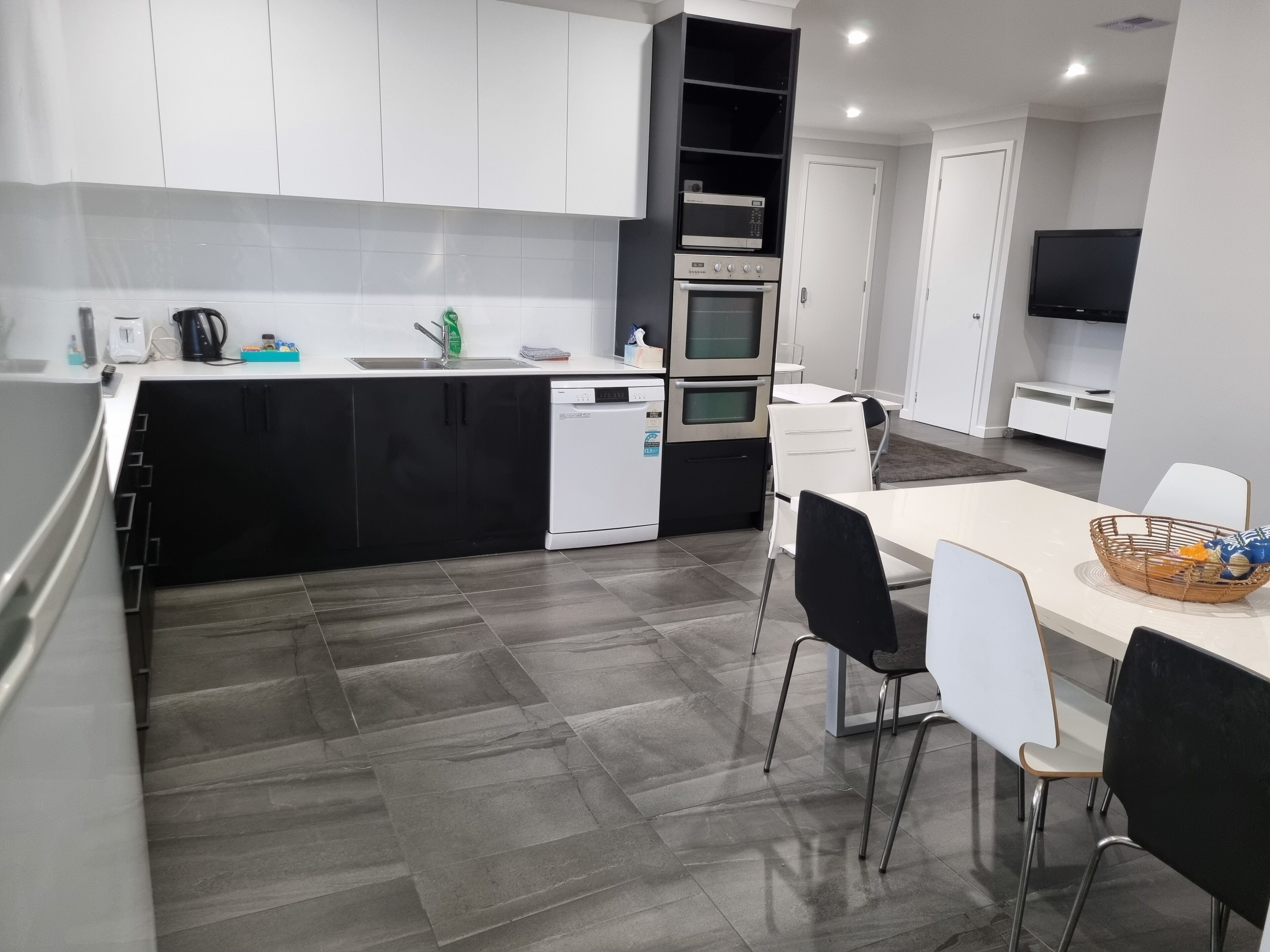 Una cucina moderna con lavastoviglie, forno e microonde. C'è una zona pranzo con tavolo e sedie.