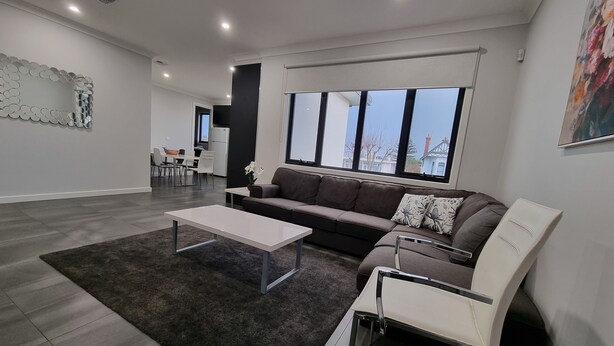 Una sala de estar moderna con un sofá gris, una mesa de centro blanca y una alfombra negra.