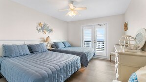 A bedroom with two beds, a ceiling fan, a nightstand with a lamp, a dresser, and a window with blinds. - Beachfront!! with Private Access to Beach (Surfside Beach)