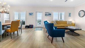 A modern living room with a wooden dining table, blue chairs, a yellow sofa, and a black coffee table. - Beachfront!! with Private Access to Beach (Surfside Beach)