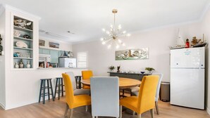 A modern kitchen with white cabinets, a round wooden table, and yellow chairs. - Beachfront!! with Private Access to Beach (Surfside Beach)