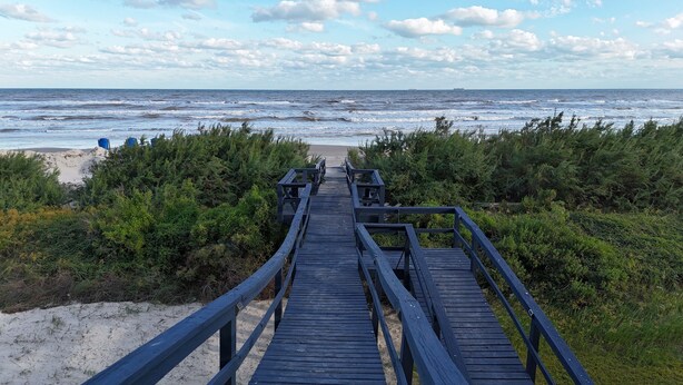 A wooden boardwalk leading to a sandy beach with dense greenery on both sides. - Beachfront!! with Private Access to Beach (Surfside Beach)