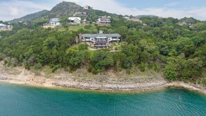 Una propiedad costera con varias casas en una ladera, con vistas al mar turquesa.