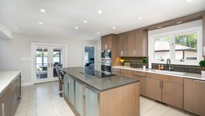 A modern kitchen with a large island, stainless steel appliances, and wooden cabinets.