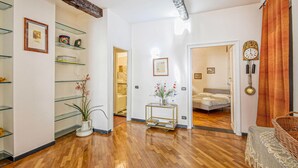 A spacious hallway with wooden flooring, a glass display unit, and a bed in the adjacent room. - Amazing apartment in Genova with WiFi (Genova)